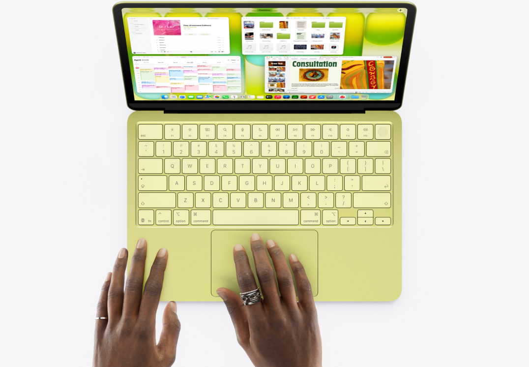青橘黃色 MacBook Neo，一隻手放在觸控式軌跡板上，螢幕上打開多個視窗，包括音樂、行事曆和 Microsoft PowerPoint app