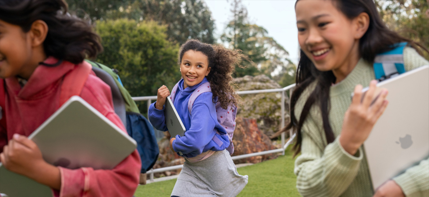 Three students running outdoors, each carrying a MacBook, highlighting lightweight, durable devices that are easy to take anywhere