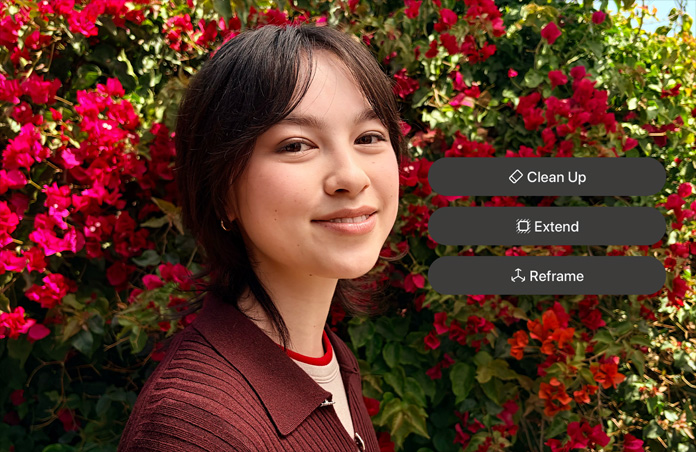 Foto einer lächelnden Person mit braunen Haaren, die einen braunen Pullover trägt und von roten Blumen umgeben ist, AI Demo für die Fotobearbeitung mit den Optionen Bereinigen, Erweitern, Neu ausrichten, die über dem Foto angezeigt werden