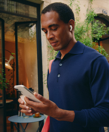 Una persona in una strada di città che guarda il suo iPhone, il dispositivo mantiene una connessione Wi‑Fi stabile mentre passa da una rete all’altra